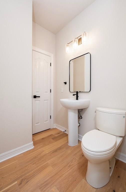 bathroom featuring a sink, baseboards, toilet, and wood finished floors