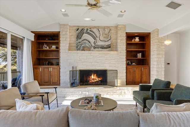 living area featuring a stone fireplace, lofted ceiling, built in features, and visible vents