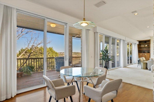 sunroom with plenty of natural light, visible vents, and vaulted ceiling