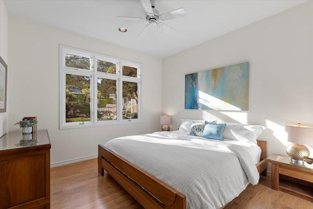 bedroom with a ceiling fan, baseboards, and wood finished floors