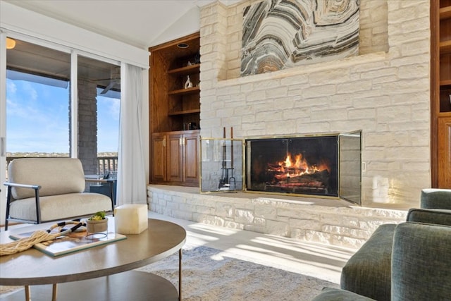 living room with built in shelves, a fireplace, and vaulted ceiling