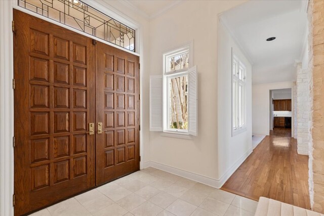 entrance foyer featuring crown molding, light tile patterned floors, and baseboards