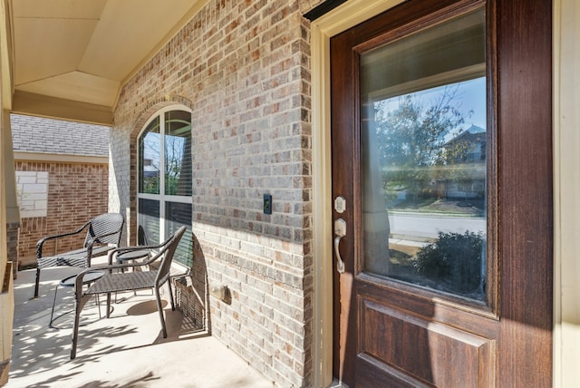 property entrance with brick siding and a porch