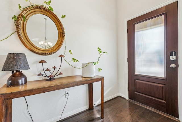 entrance foyer featuring a wealth of natural light, baseboards, a notable chandelier, and dark wood finished floors