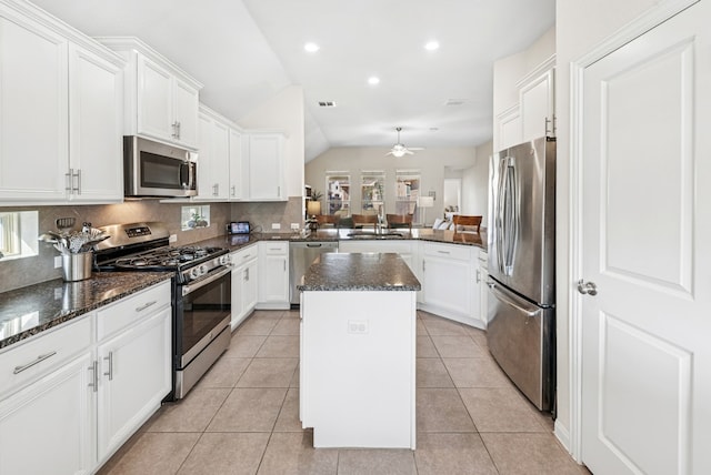 kitchen featuring a sink, tasteful backsplash, a kitchen island, stainless steel appliances, and light tile patterned flooring