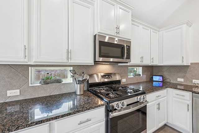 kitchen with white cabinetry, decorative backsplash, dark stone counters, and stainless steel appliances