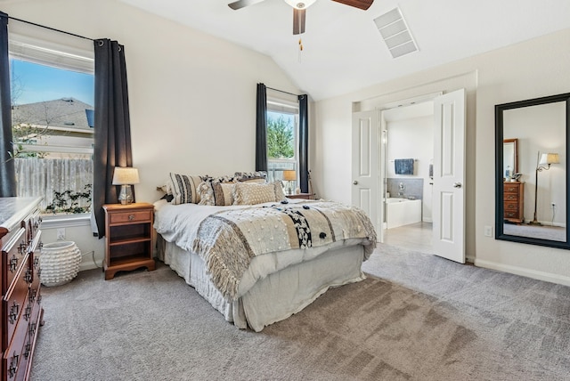 bedroom featuring visible vents, light colored carpet, ensuite bath, and vaulted ceiling