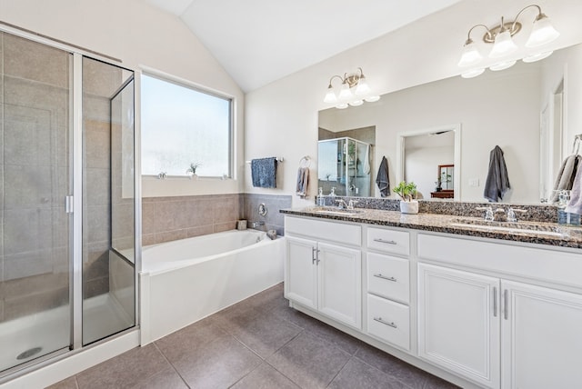 bathroom featuring tile patterned flooring, lofted ceiling, double vanity, a stall shower, and a sink