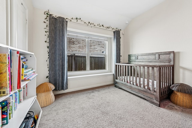 bedroom featuring carpet floors, a crib, and vaulted ceiling