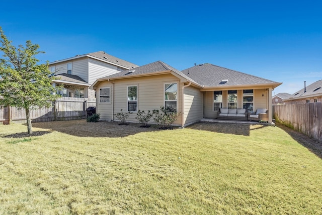 rear view of property with a lawn, roof with shingles, and a fenced backyard