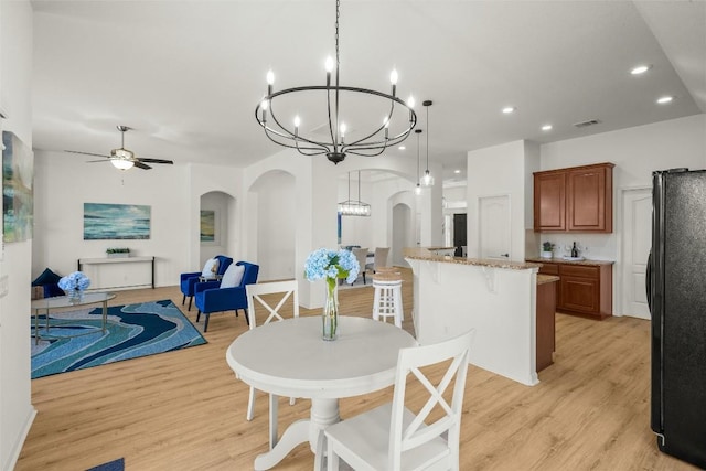 dining room featuring visible vents, recessed lighting, light wood-style flooring, ceiling fan with notable chandelier, and arched walkways