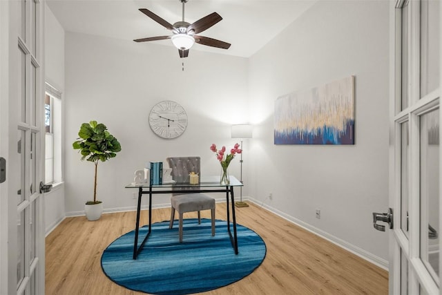 office area with a ceiling fan, light wood-type flooring, and baseboards