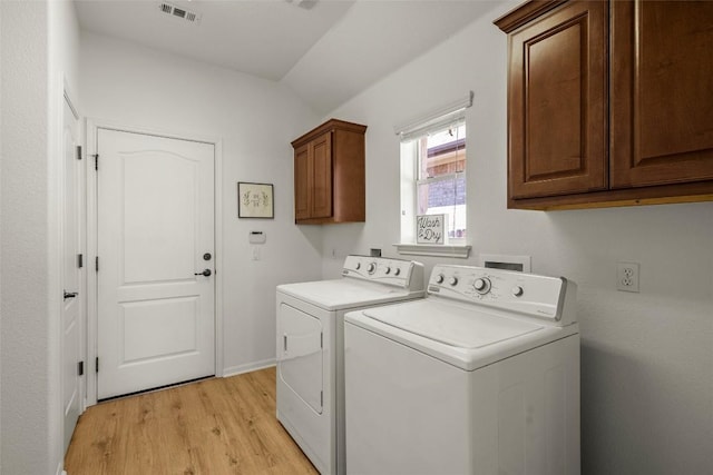 clothes washing area featuring visible vents, cabinet space, separate washer and dryer, and light wood-style flooring