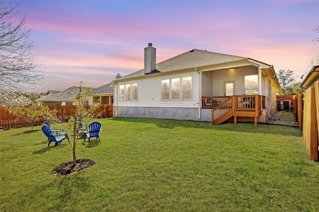 back of house featuring a yard, a chimney, and a fenced backyard