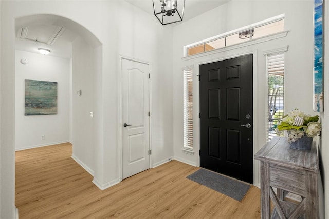 foyer featuring a notable chandelier, baseboards, and light wood-style floors