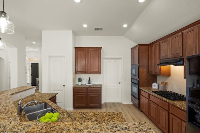 kitchen with visible vents, black appliances, a sink, under cabinet range hood, and lofted ceiling