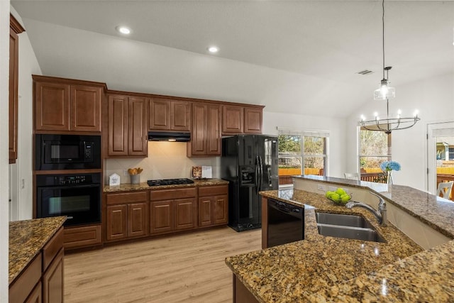 kitchen with under cabinet range hood, lofted ceiling, light wood-style flooring, black appliances, and a sink