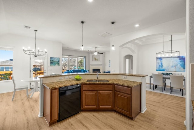 kitchen with a sink, brown cabinets, black dishwasher, and light wood finished floors