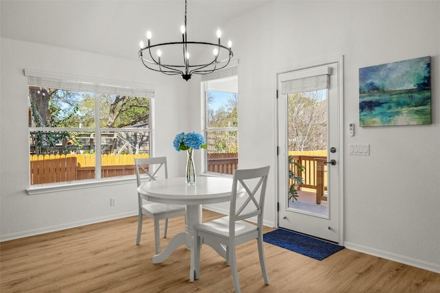 dining area featuring baseboards, plenty of natural light, an inviting chandelier, and wood finished floors