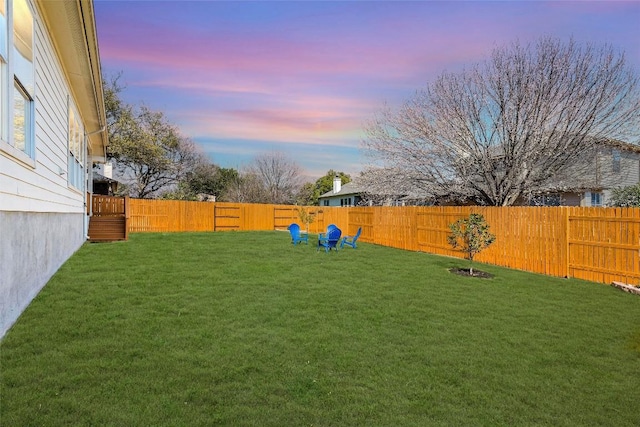 yard at dusk featuring a fenced backyard