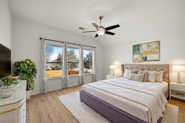 bedroom featuring light wood finished floors, visible vents, baseboards, lofted ceiling, and a ceiling fan