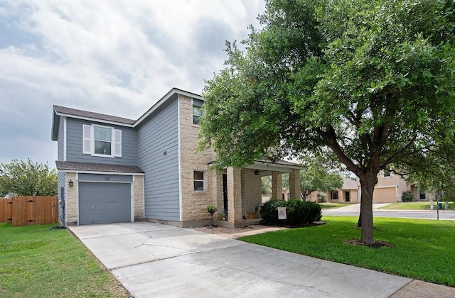 view of front of home with a front yard, fence, driveway, an attached garage, and stone siding