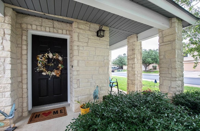 property entrance with stone siding and a porch