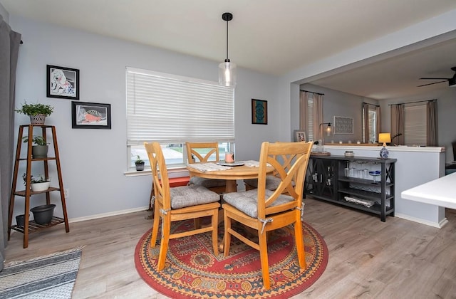 dining space with baseboards, light wood finished floors, and ceiling fan