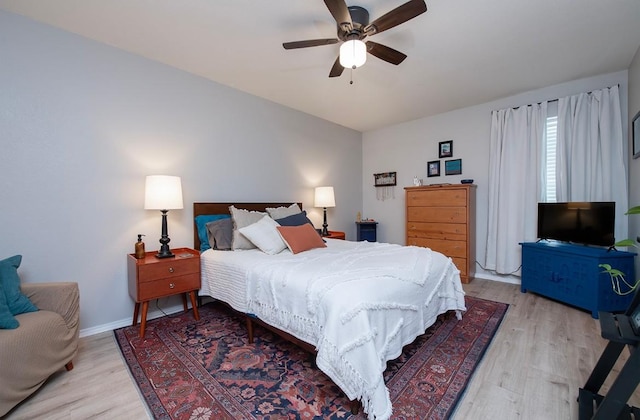 bedroom with vaulted ceiling, light wood-style flooring, baseboards, and ceiling fan