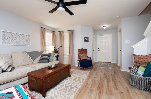 living room with baseboards, a ceiling fan, and light wood finished floors