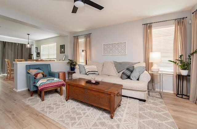 living room with baseboards, plenty of natural light, light wood-style floors, and a ceiling fan