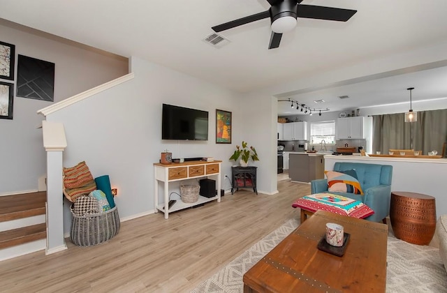 living room with visible vents, track lighting, a ceiling fan, stairway, and light wood finished floors