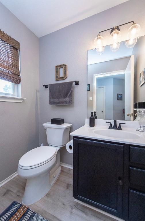 bathroom featuring toilet, vanity, baseboards, and wood finished floors