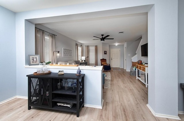 interior space with visible vents, a ceiling fan, baseboards, and wood finished floors