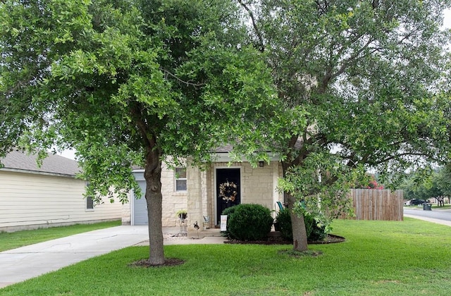 obstructed view of property with fence, a front yard, a garage, stone siding, and driveway