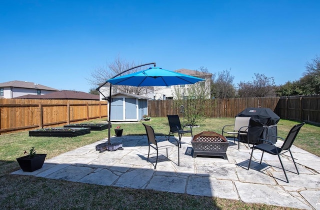 view of patio with grilling area, a shed, an outdoor fire pit, a garden, and an outbuilding