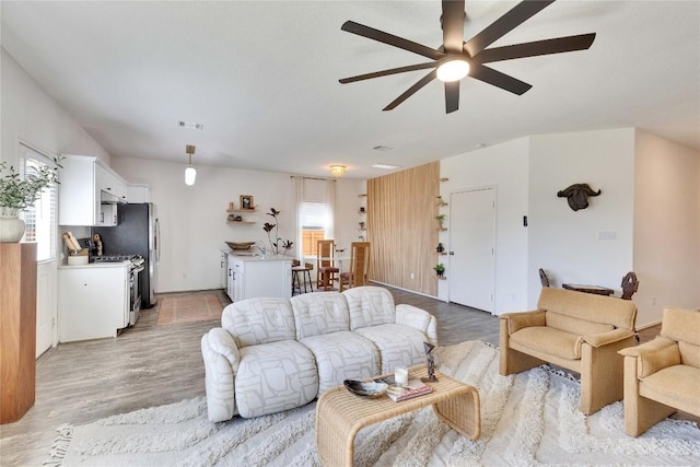 living area featuring light wood-type flooring, visible vents, and a ceiling fan