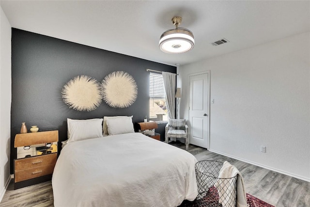 bedroom featuring visible vents, baseboards, and wood finished floors