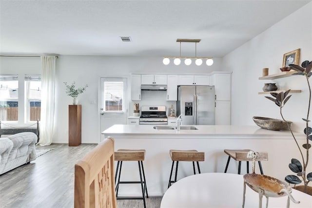 kitchen with a kitchen bar, visible vents, a sink, stainless steel appliances, and light wood-style floors