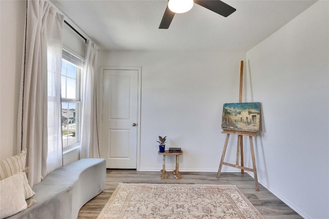 sitting room featuring light wood-type flooring, baseboards, and a ceiling fan