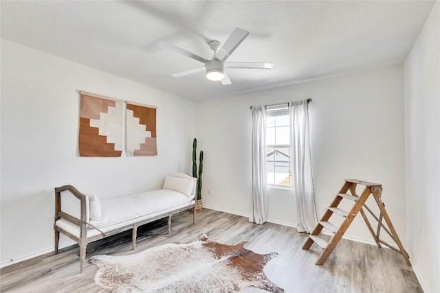 living area featuring a textured ceiling, baseboards, a ceiling fan, and wood finished floors