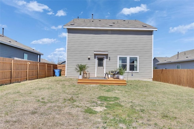 back of property with a deck, a fenced backyard, and a lawn