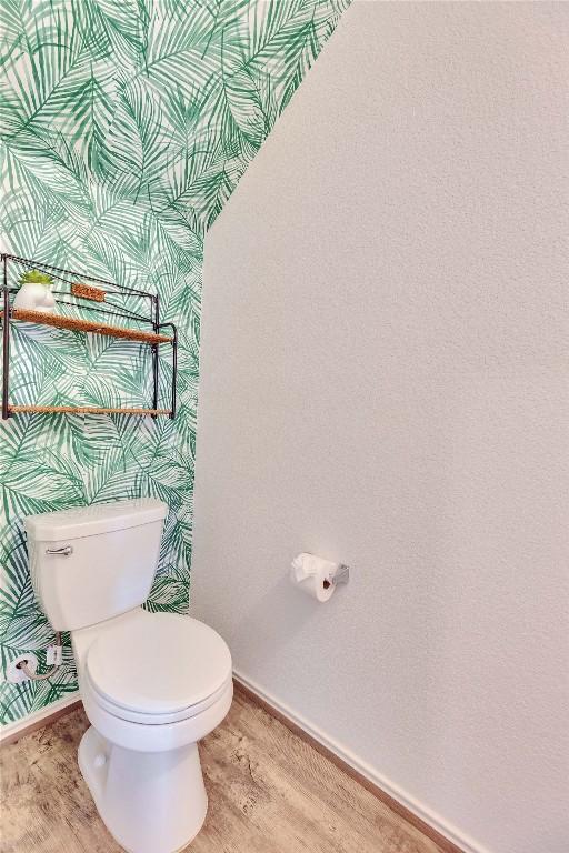 bathroom with toilet, wood finished floors, and baseboards