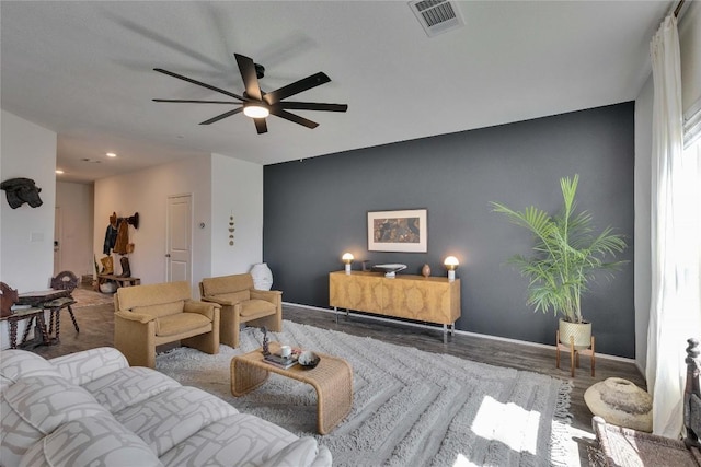 living room featuring visible vents, baseboards, a ceiling fan, and wood finished floors