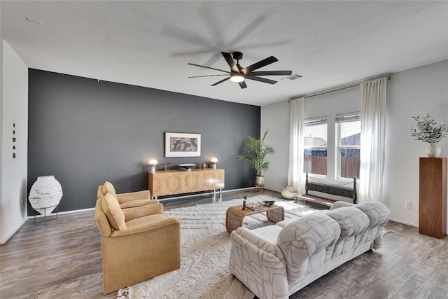 living room with visible vents, a textured ceiling, ceiling fan, and wood finished floors