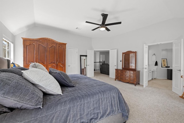 bedroom featuring visible vents, ceiling fan, light colored carpet, lofted ceiling, and ensuite bath