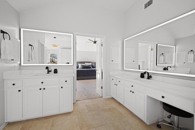 bathroom with visible vents, two vanities, lofted ceiling, and a sink