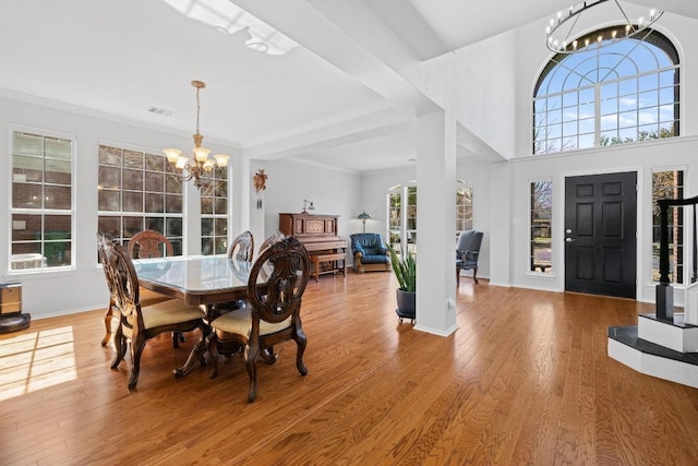 dining space featuring visible vents, wood finished floors, an inviting chandelier, crown molding, and baseboards