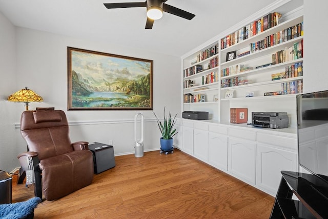 sitting room featuring built in features, a ceiling fan, light wood-type flooring, and baseboards