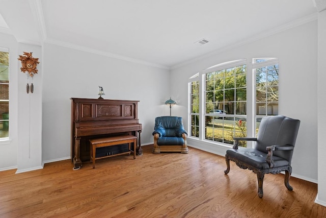 sitting room featuring visible vents, baseboards, wood finished floors, and crown molding